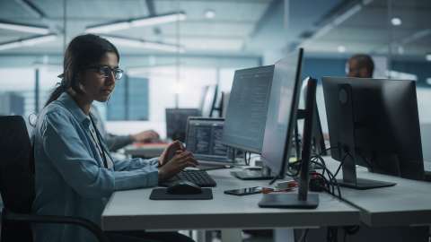 Femme travaillant dans un bureau sur un PC de bureau avec deux écrans