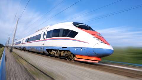 Train de passagers d'aspect moderne se déplaçant rapidement sur des voies ferrées à côté d'un paysage agricole