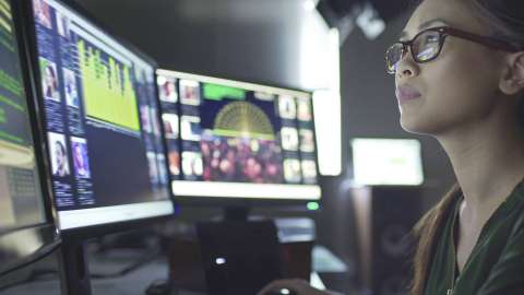 Une vue rapprochée d'une personne portant des lunettes et examinant des données et des images affichées sur plusieurs écrans d'ordinateur